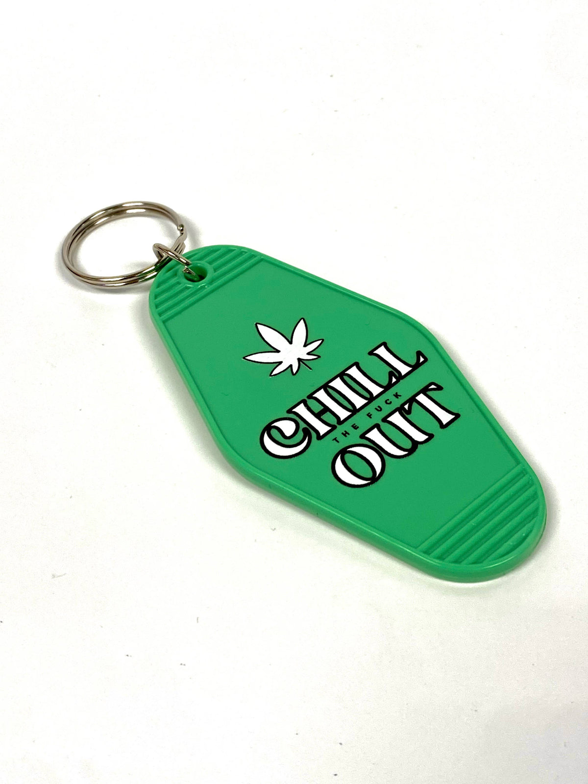 The Properly Improper Chill The Fuck Out keychain features a green embossed design with a white cannabis leaf, bold lettering, and a silver ring—making it stand out among our top sellers.
