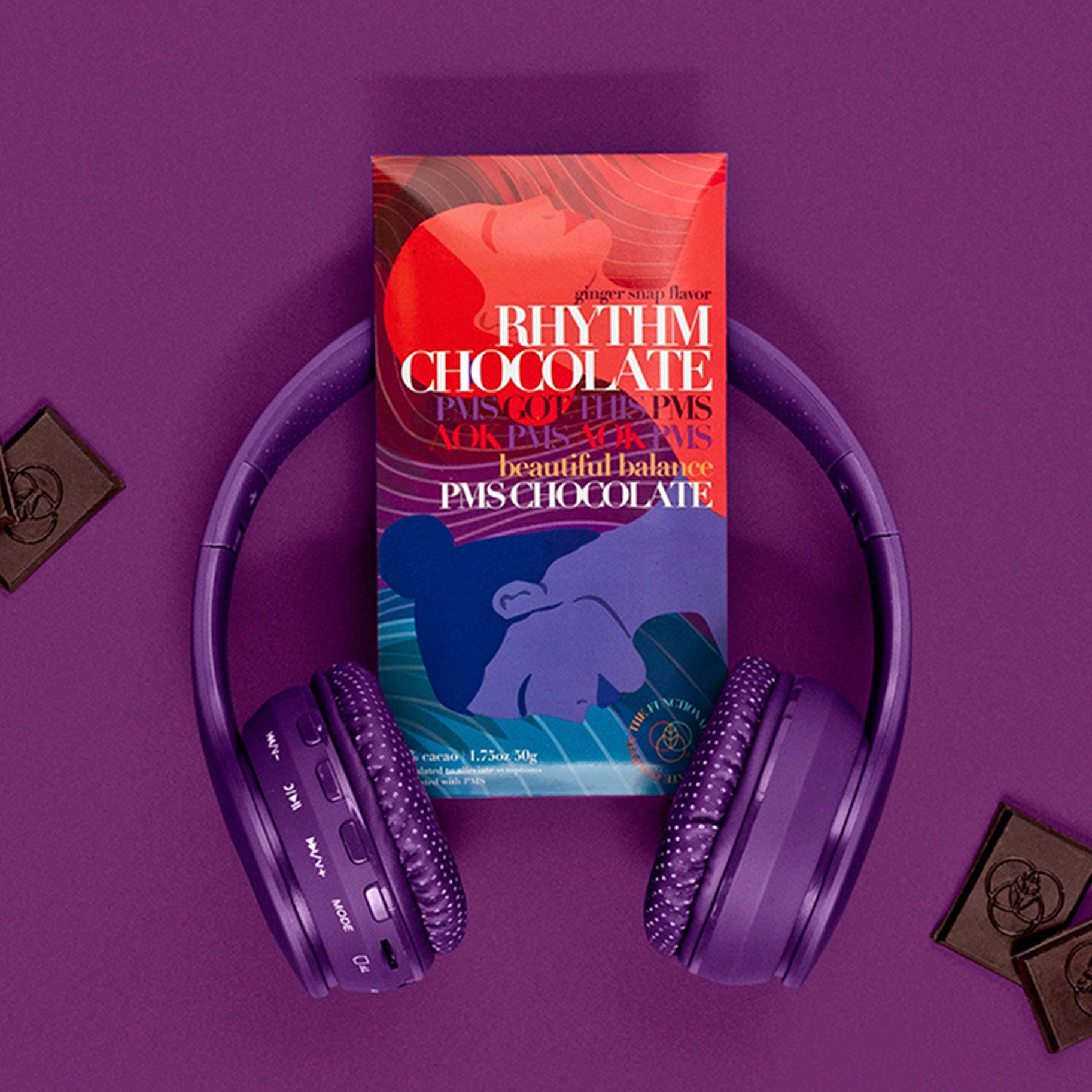 The Functional Chocolate Companys Rhythm Chocolate - PMS Formula bar with bold text and abstract faces sits on purple wireless headphones, surrounded by chocolate squares on a purple background for mood support.
