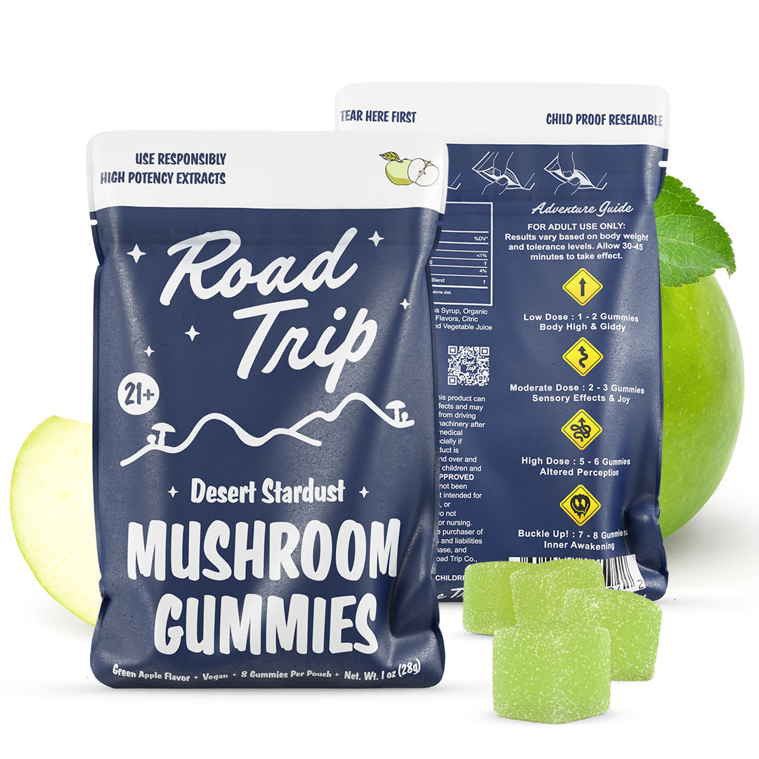 Two blue resealable bags labeled Road Trip Mushroom Gummies by Road Trip are shown with green gummies, a green apple slice, and a mint leaf beside them. The packaging displays usage instructions and dosage guidelines.