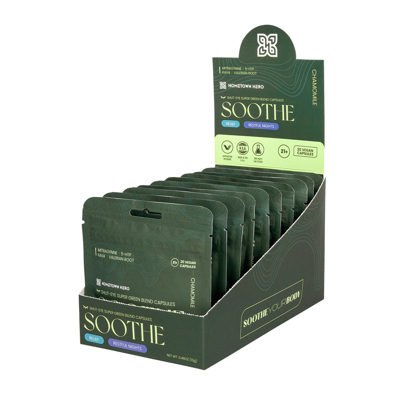 A display box of Hometown Hero Kratom Soothe Capsules features green packaging with blue and white accents, highlighting benefits like relaxation, restful nights, and a calming Kratom blend.