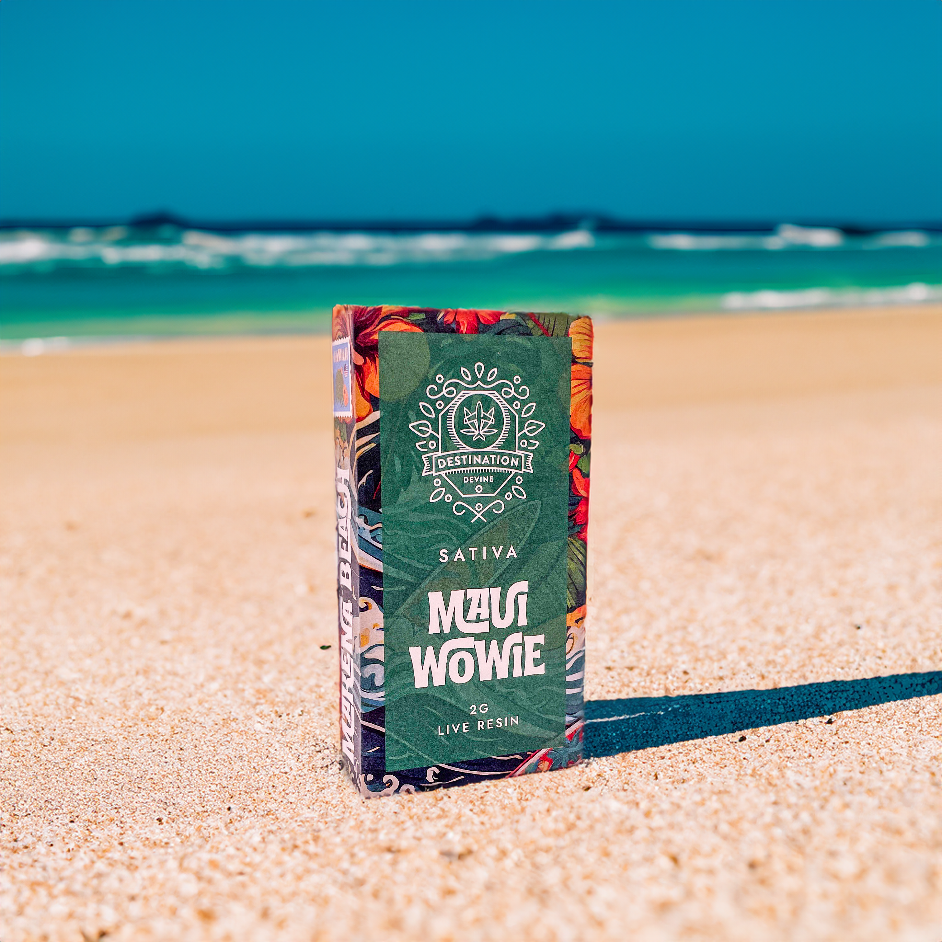 A vibrant DeVINE Destinations Live Resin THC Disposable by DeVINE Wellness stands upright on a sandy beach with clear blue sky and ocean waves, evoking travel vibes and premium cannabis relaxation.