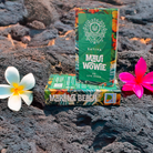 Two vibrant deVINE Destinations Live Resin THC Disposable boxes by DeVINE Wellness—Maui Wowie and Makena Beach—rest on volcanic rocks amid tropical flowers, perfect for a premium, travel-inspired cannabis vape experience.