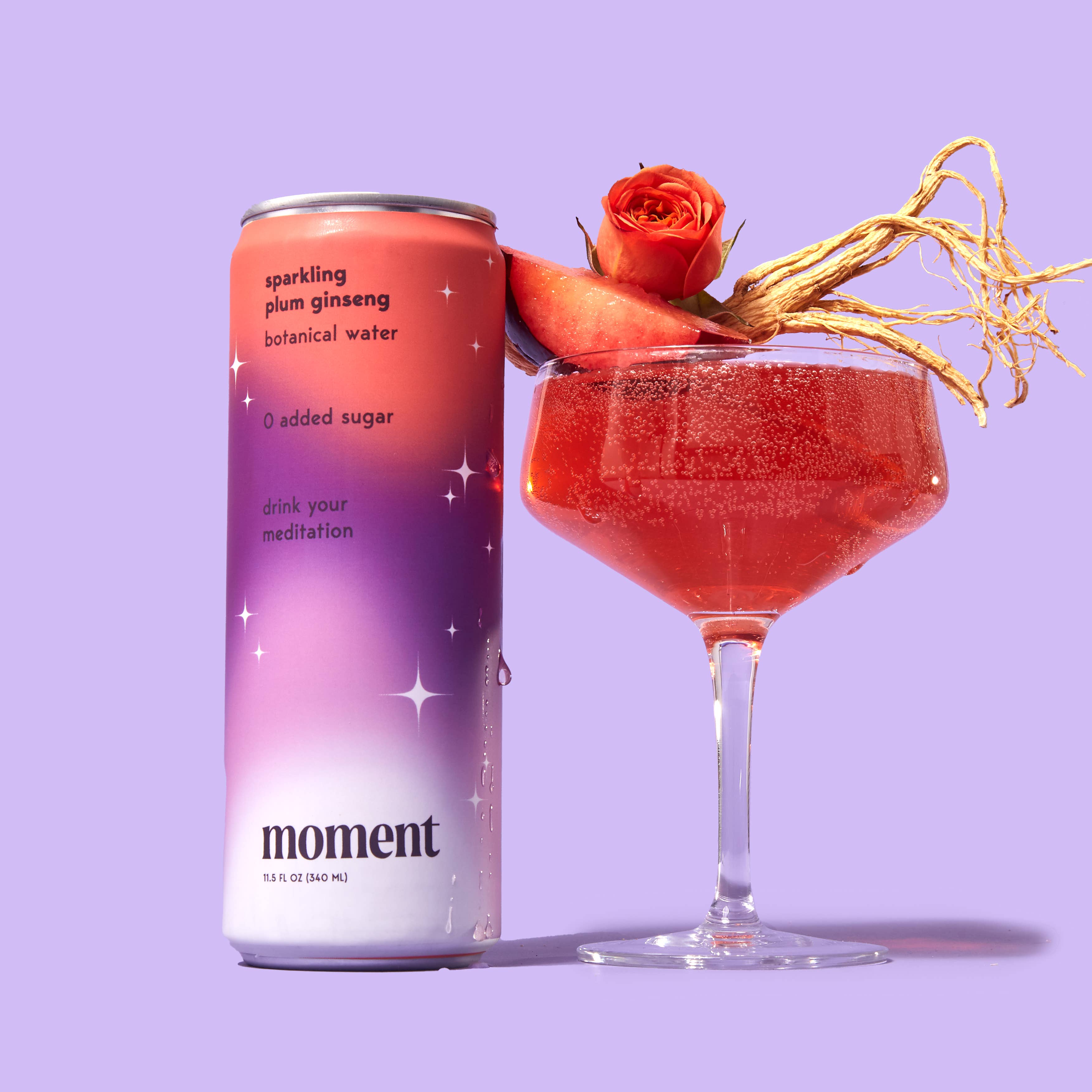 A can of Moment Botanical Beverage stands beside a glass of red drink garnished with peach, rose, and ginseng root on a purple background—your meditation in a can from Moment’s natural botanical beverage.