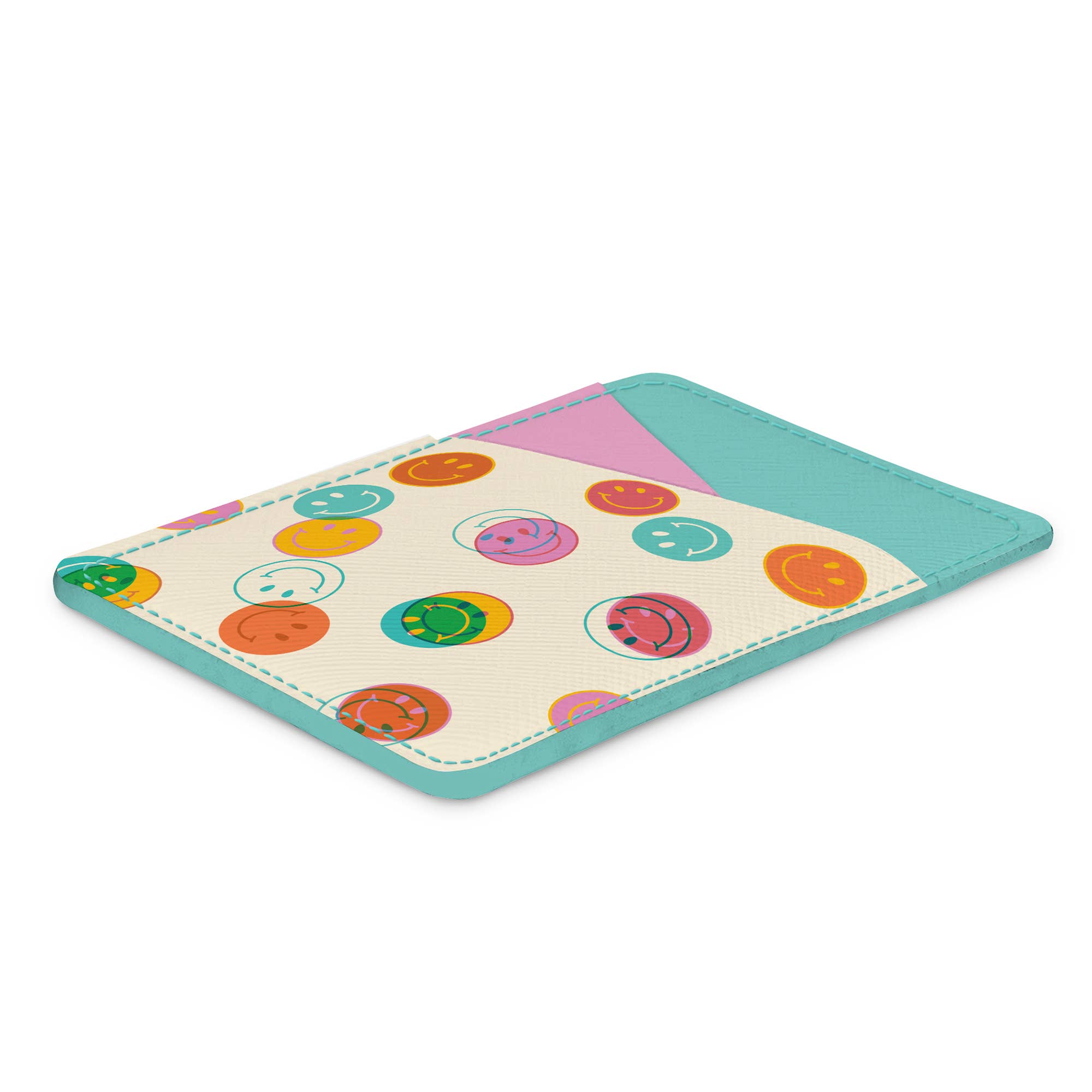 The Studio Oh! Smiley Trails Stick-On Cell Phone Wallet is a slim, rectangular vegan leather wallet with a teal border, pastel pink accent, and a cream front decorated with colorful smiling and winking faces, shown flat on a white background.