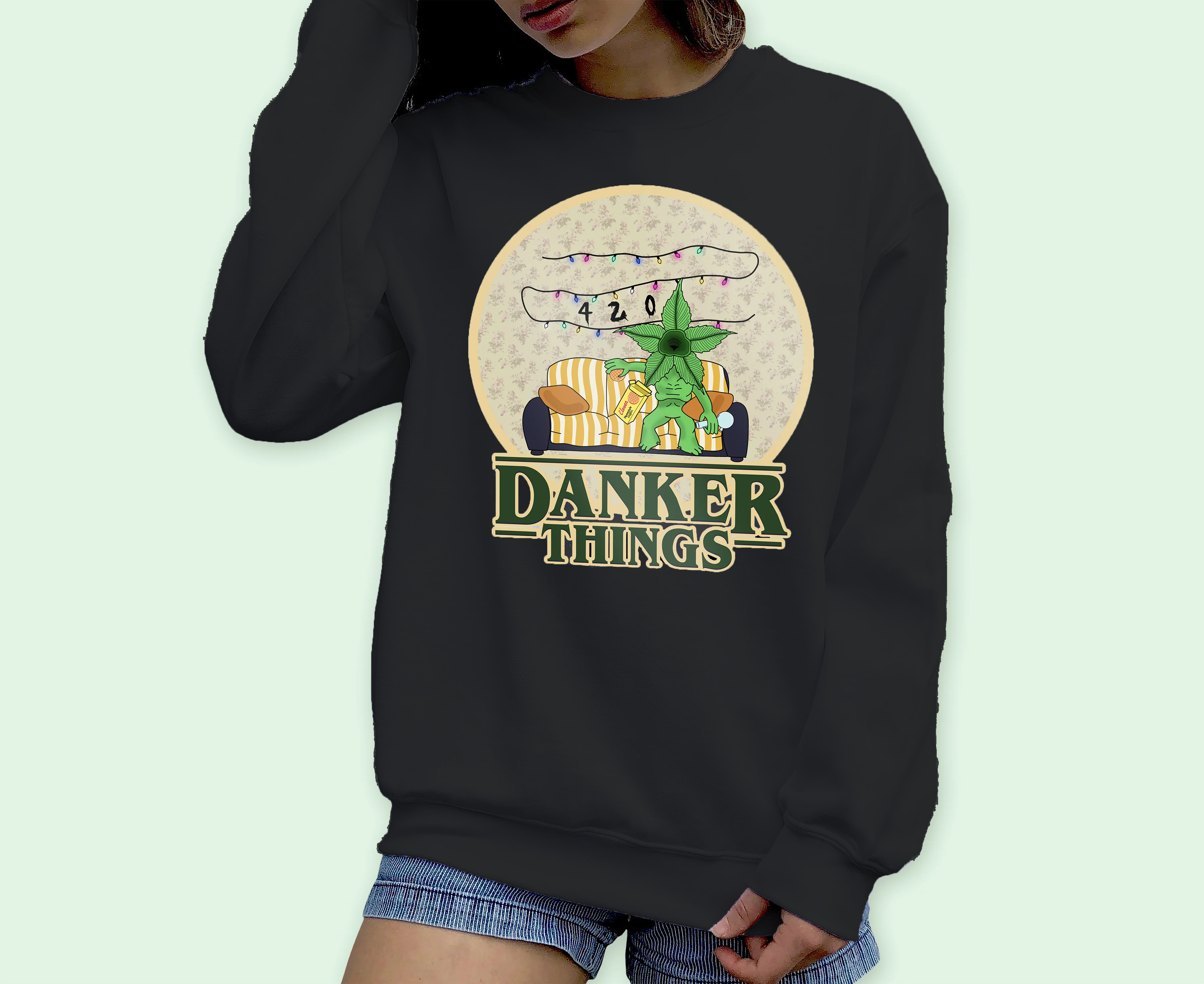 A person wears the HiCiti Danker Things Crewneck Sweatshirt in black, featuring two cartoon characters on a couch with 420 above and DANKER THINGS below—a playful nod to 80s nostalgia and iconic pop culture.