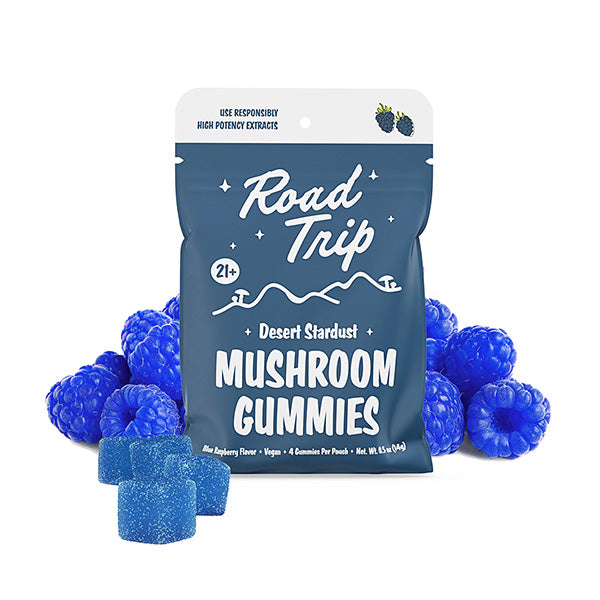 A blue bag of Road Trip Mushroom Gummies stands out among vegan gummies and blue raspberries. The package highlights 21+, blue raspberry flavor, plant-based ingredients, and the Road Trip brand.