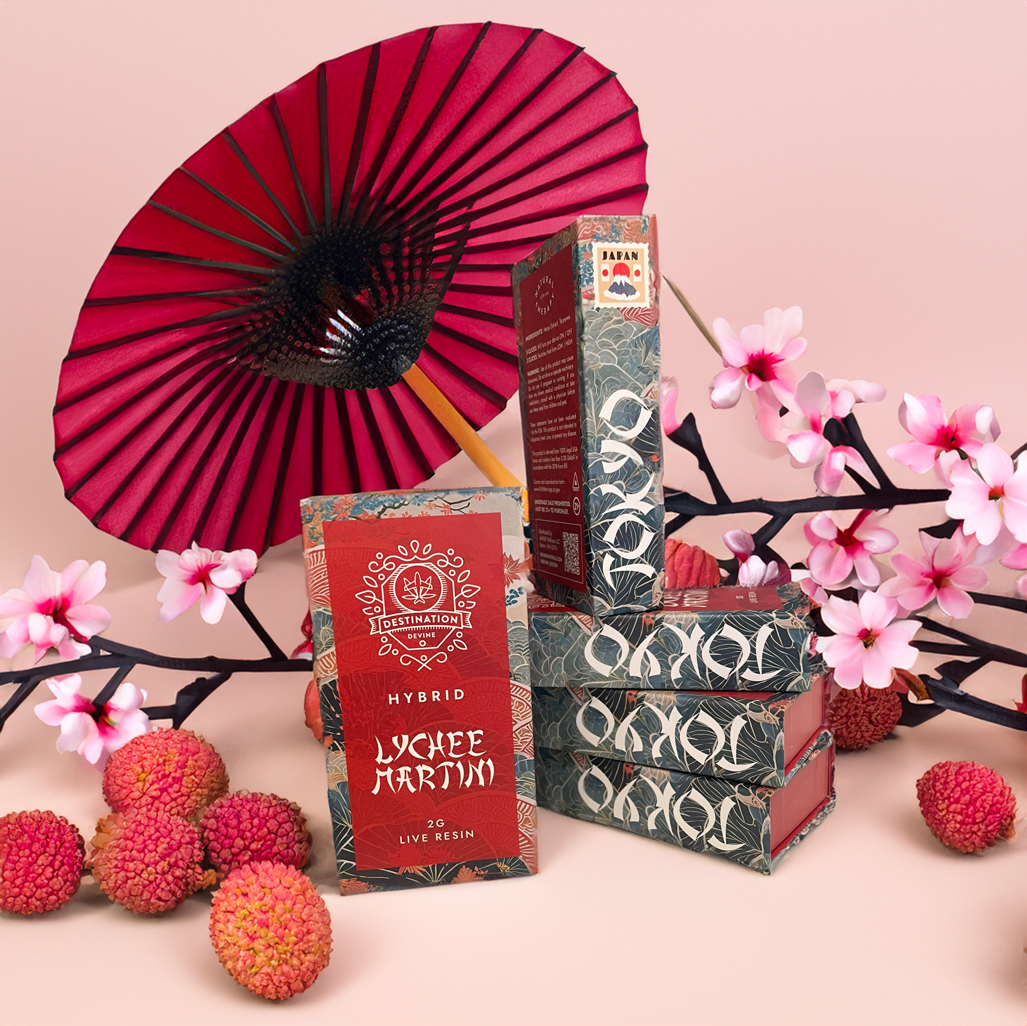 Boxes of deVINE Destinations Live Resin THC Disposable by DeVINE Wellness are shown with lychee fruit, pink cherry blossoms, and a red parasol on a pastel pink background, creating an elegant, travel-inspired display.