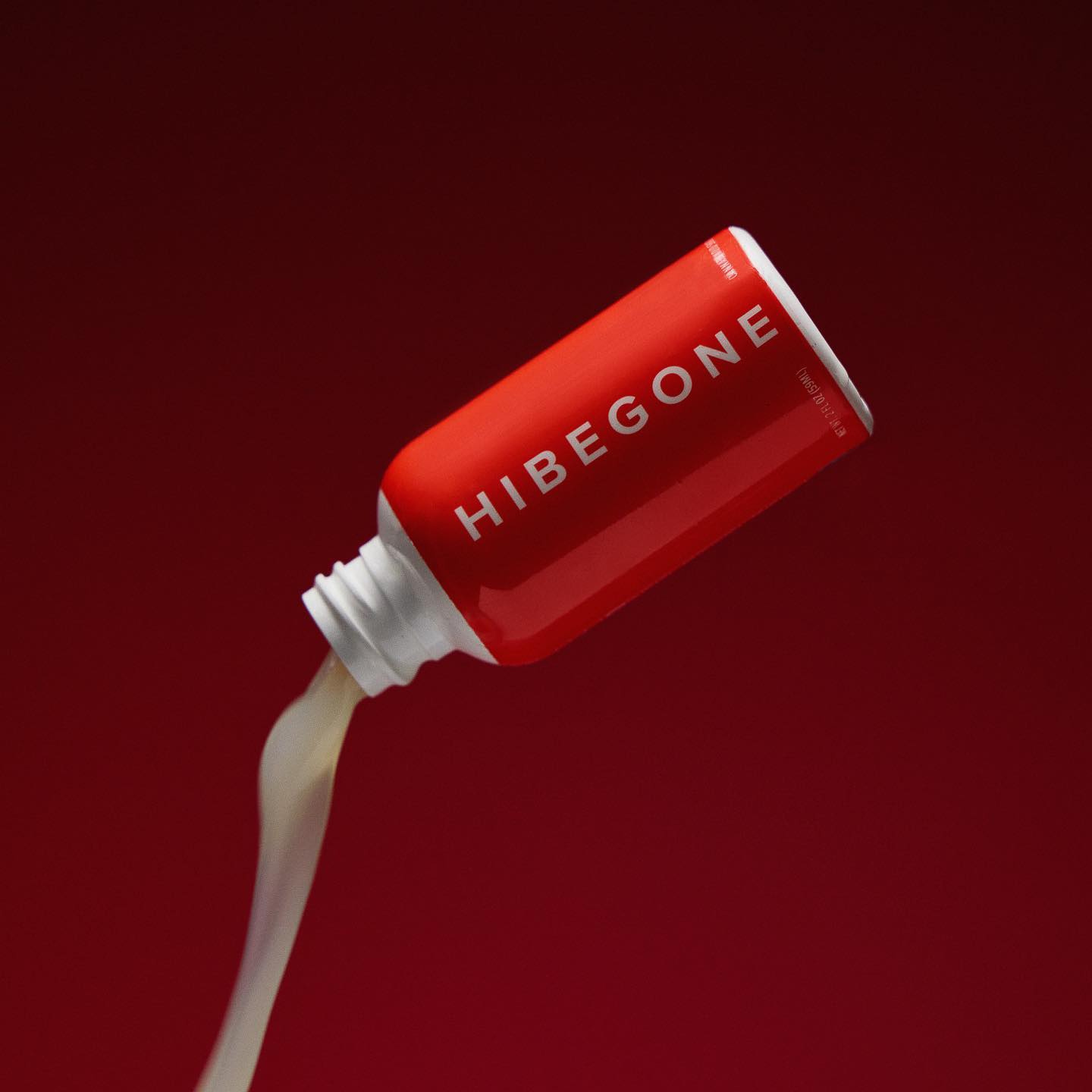 A red HIBEGONE bottle by Hibegone tips over, pouring a pale liquid against a deep red background—ideal for THC detox or fast cannabis side effects relief.