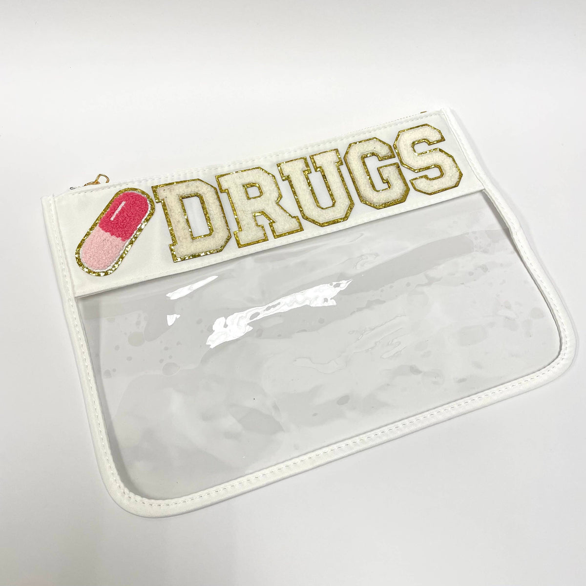 The Properly Improper Drugs Pill White/Clear Nylon Pouch features chenille DRUGS letters, a pink and white capsule patch, and a zippered clear design—ideal for storing cosmetics or school supplies.