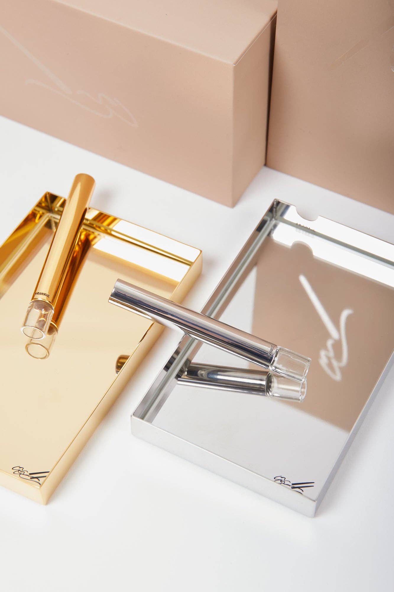 Ashtray + Pipe Set with gold and silver ashtrays featuring elegant 1-hitter pipes and clear glass resting plates.