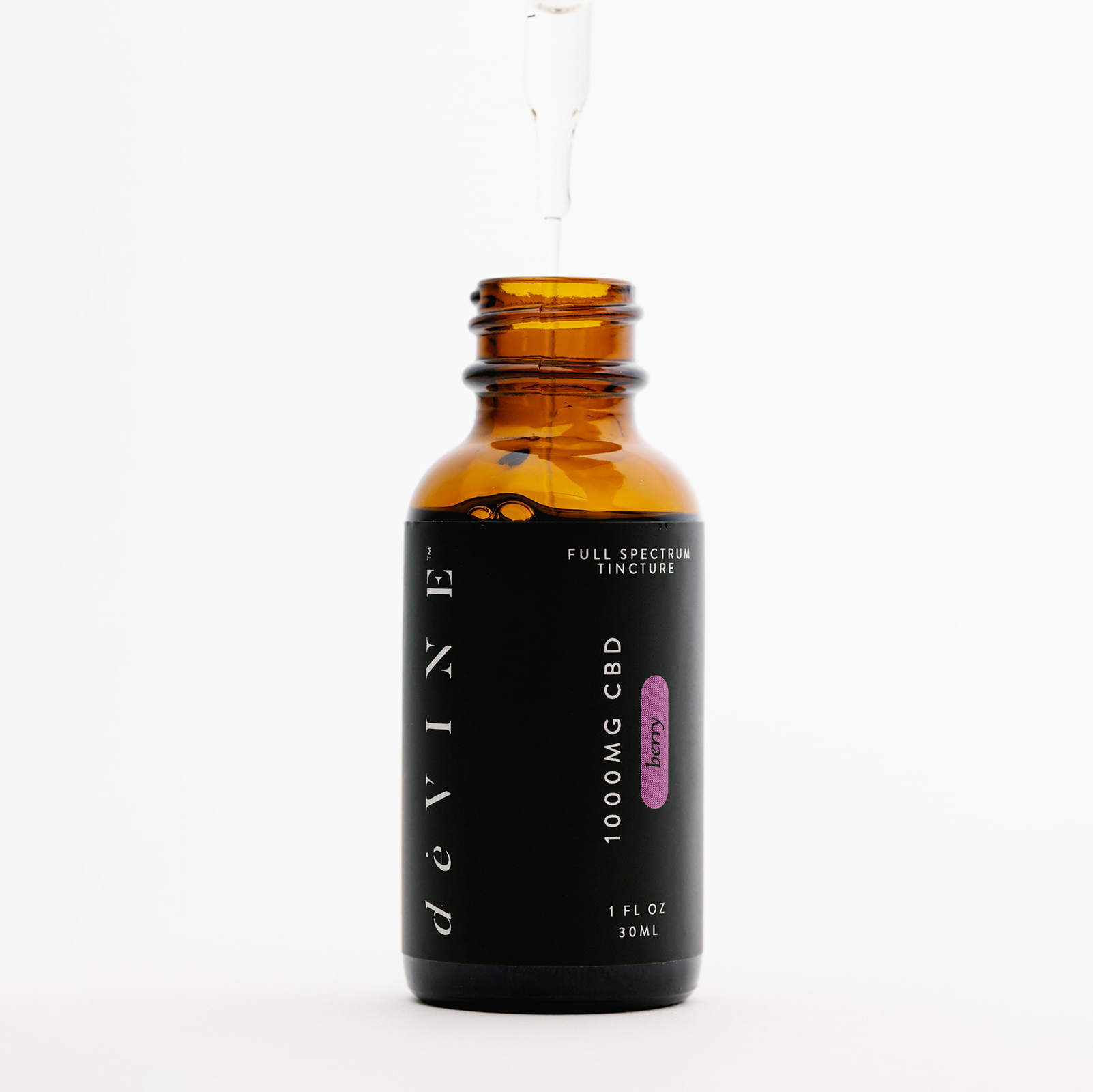 A brown glass bottle labeled DeVINE Wellness 1000mg Full Spectrum Tincture, 1 FL OZ (30ml), with a black dropper holding liquid above the bottle. Set against a white background, this organic CBD oil is ideal for relaxation.