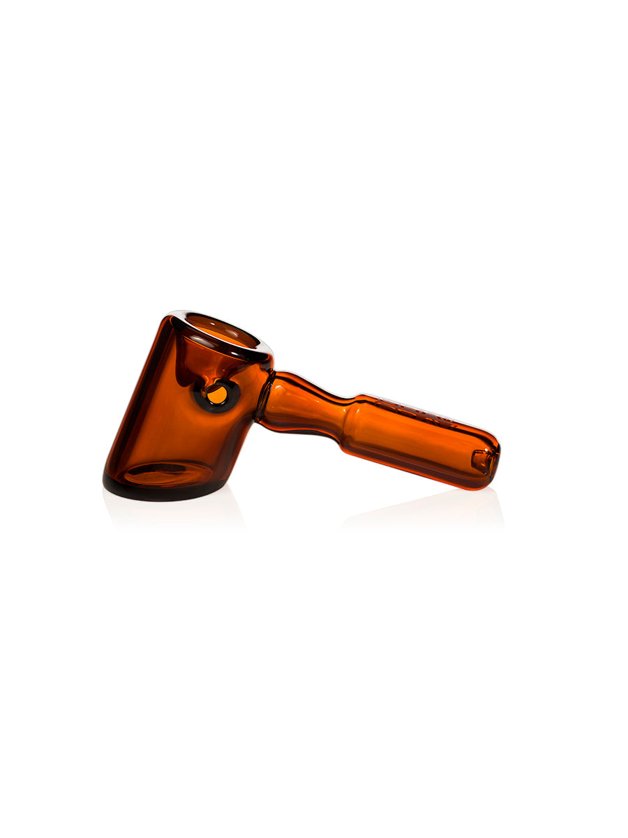 The GRAV Hammer Hand Pipe is a brown, translucent piece with a rounded bowl, straight handle, ash catching chamber, and flat base. It’s displayed on a white background.